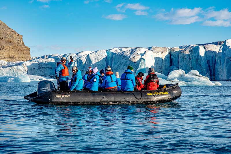 Adventure Canada - People in a boat looking at a glacier