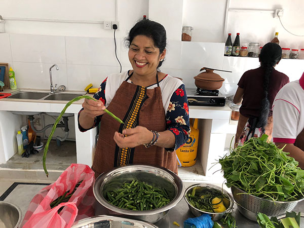 Woman smiling making food wearing an apron in a white kitchen - Just You Travel