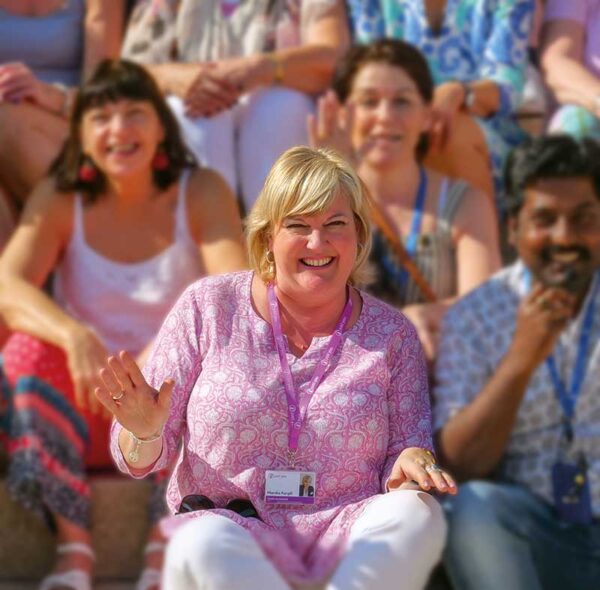 Holiday Director - Just You - woman in pink sitting with group of other people smiling